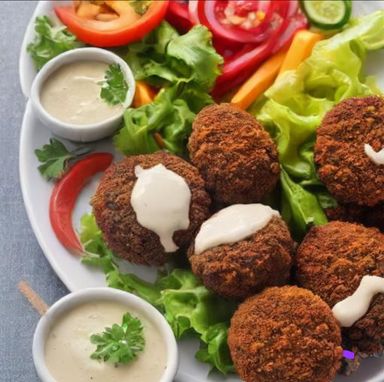 Ta'amiya (Egyptian Falafel): Deep-fried patties made from ground fava beans, herbs, and spices. Accompanied by tahini sauce and fresh vegetables.