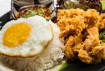 Crispy marinated popcorn chicken rice served with sunny side up and Thai chilli